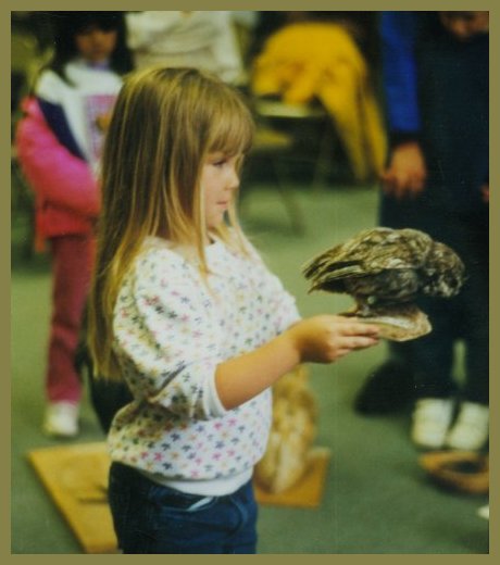 Small girl proudly carries bird around to be examined by other children